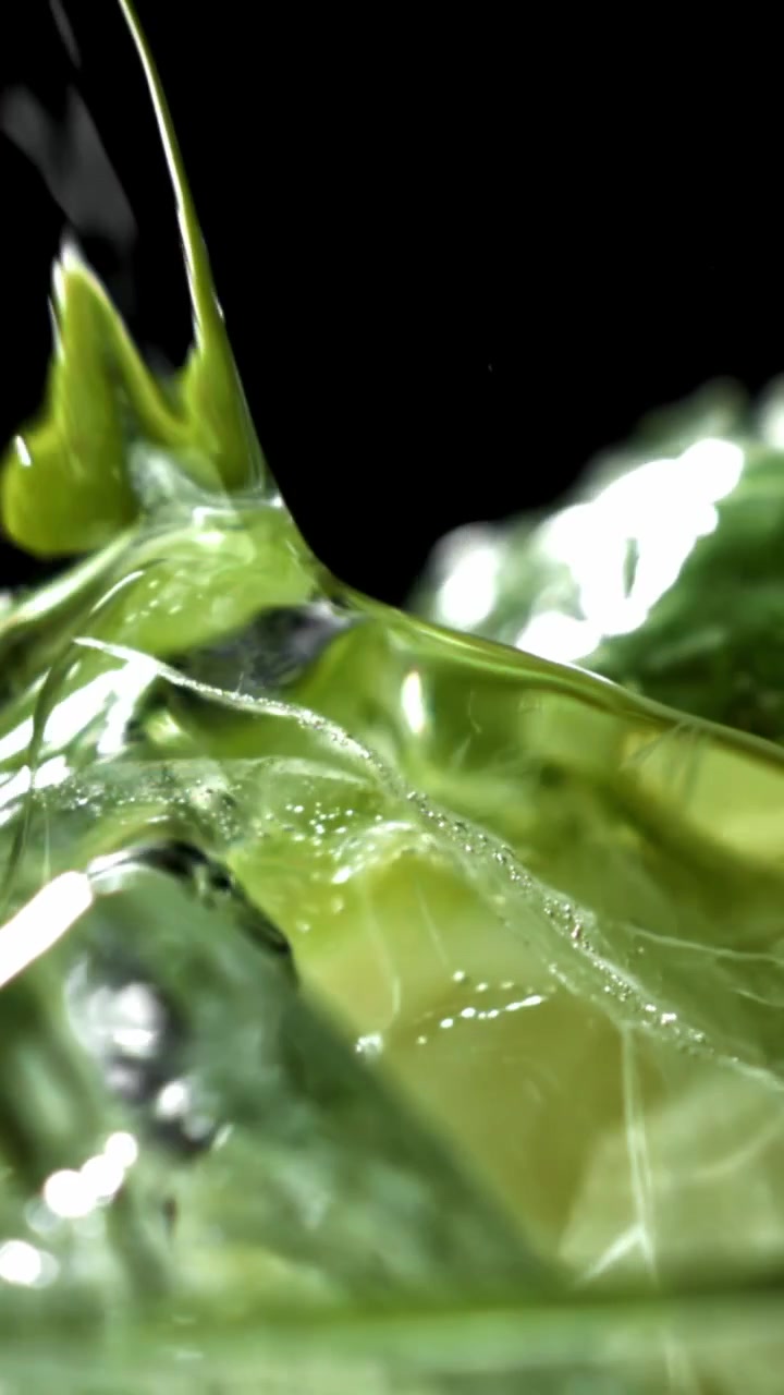 Liquido verde rinfrescante versato su cubetti di ghiaccio al rallentatore