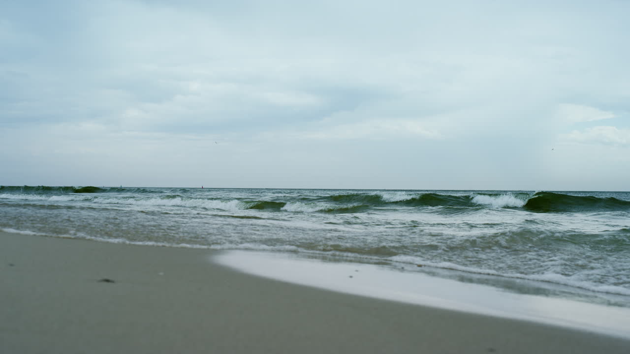 파도가 모래 해변에 부 ⁇ 히고 회색 구름이 나는 날씨. 공중 뷰 바다 폭풍.