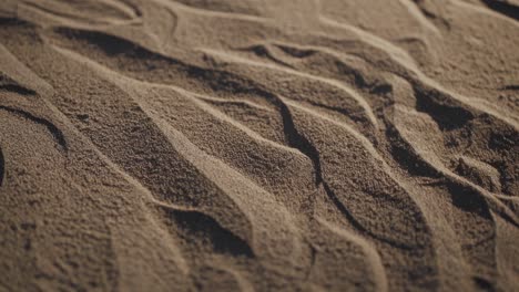 close-up video of sand patterns with a low-angle view, capturing intricate textures and shadows