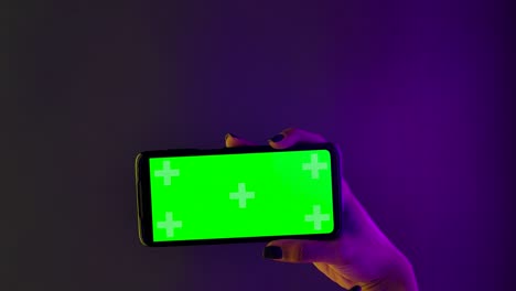 hand holding a phone with a green screen