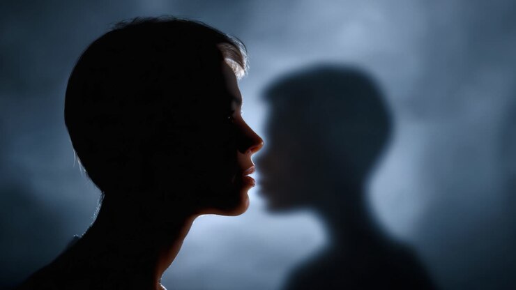 An ethereal silhouette of a woman captured against a smoky backdrop, highlighting the duality of her profile and its ghostly reflection in misty shadows