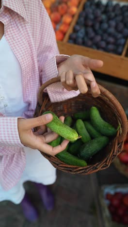 woman shopping for cucumbers at a farmers market