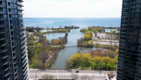 Drone-Volando-Entre-Edificios-De-Apartamentos-Sobre-Un-Río-Que-Desemboca-En-El-Lago-Ontario