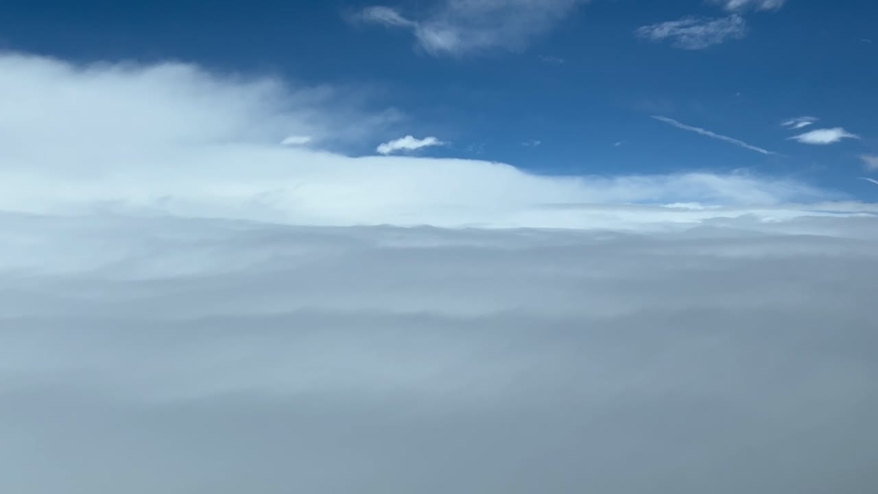 piloto inmersivo pov volando sobre un mar de nubes blancas y esponjosas con un cielo azul disparado desde la cabina de un avión