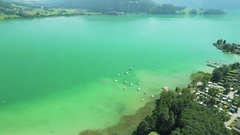 the drone reveals the serene mondsee lake, cradled by majestic mountains