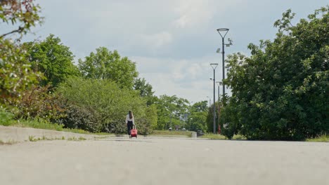 Young-Caucasian-woman-walking-down-the-road-while-pulling-a-suitcase