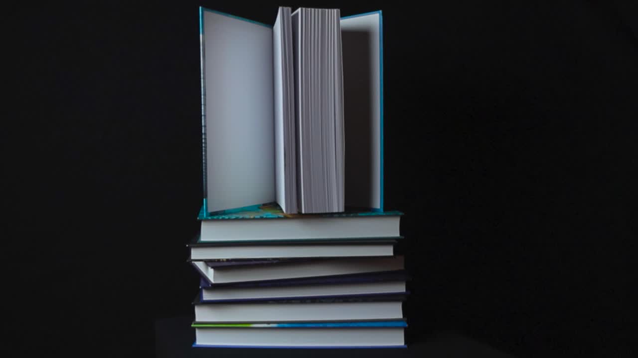 Hardcover or hardcopy colorful books with white pages on top of each other with bottom ones being stacked sideways and the book on top is opened and standing up. Books on dark black studio background.