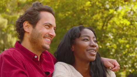 loving multi-racial couple leaning on fence on walk in summer countryside