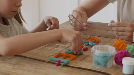 una niña rubia y su madre jugando con plastilina 1