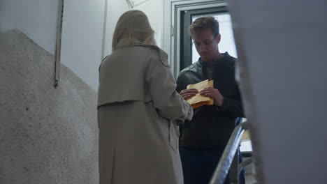 woman and man meet in staircase of building to exchange envelope with cash or payment for service. dark dirty deal or business. fraud and collusion. insider information and bribery. spy network