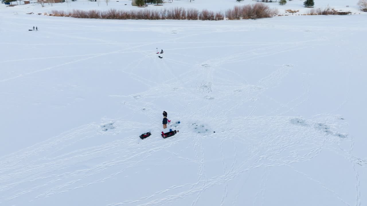 pescadores de hielo de boseman montana en un estanque suburbano congelado y nevado, rastreando a la derecha con un dron de 4k durante la hora dorada