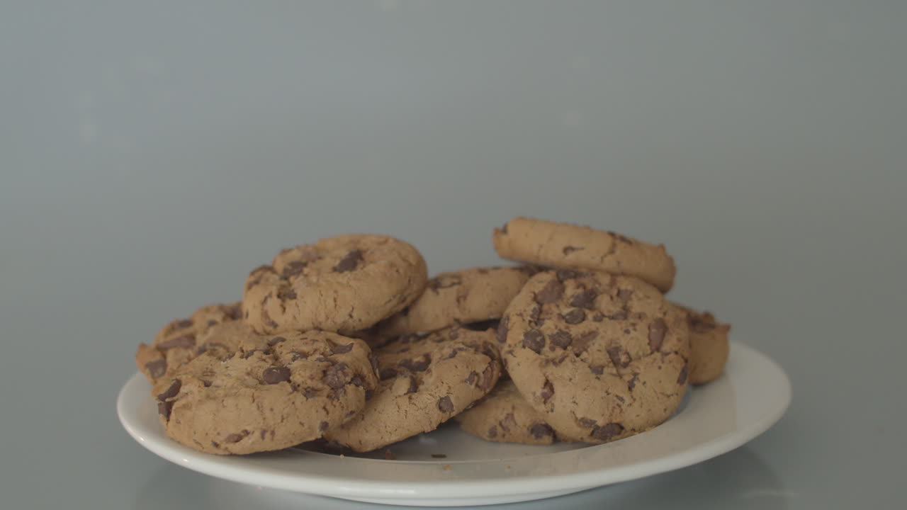 tomando a mano galletas con trocitos de chocolate de un montón de galletas - anchas