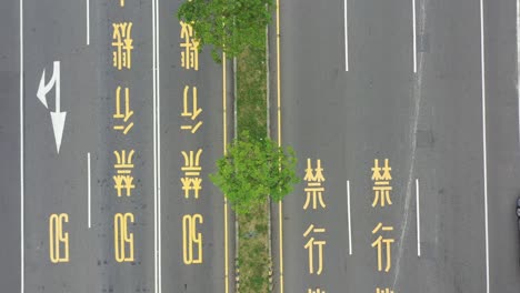 aerial drone footage of zoom out bird eye view of asphalt road and traffic in taiwan with chinese words signage of speed limit 50 and motorcycle is prohibited painted on the road