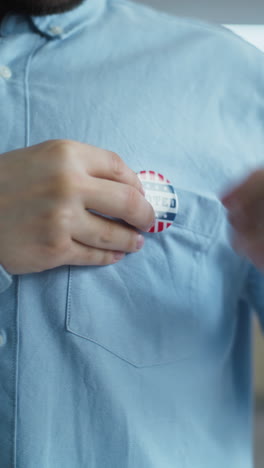 african american us citizen puts on badge with usa flag logo close up of anonymous african american man or us citizen putting on badge with usa flag logo and inscription i voted male voter at polling station after voting election day in the united states