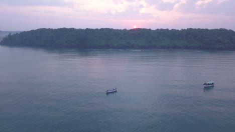 fishing boats sailing across arabian sea at sunrise in south goa, india