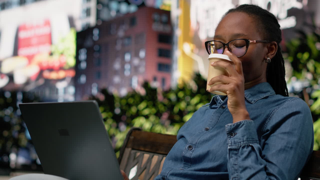 Nômade digital bebendo café e trabalhando com laptop em um banco de parque da cidade