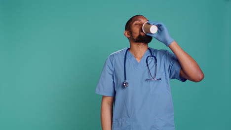 tired healthcare specialist gaining energy with cup of coffee while at work,