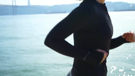 athletic girl in sportswear jogging near river