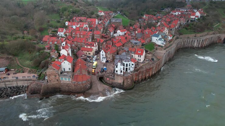 Vista aerea statica e scenografica delle case del villaggio turistico storico di Robin's Hood Bay con l'alta marea