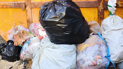 A static shot of an overflowing dumpster in Phuket, Thailand, highlighting waste management challenges. Bright daylight illuminates the scene