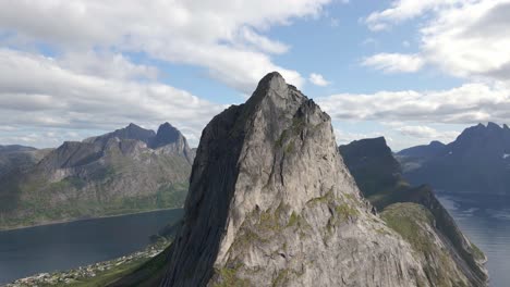 aerial orbiting shot segla senja island with rocky mountains surrounded by fjord in norway - village at coast in the valley