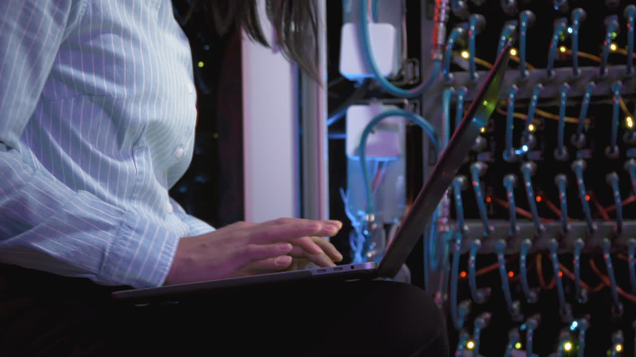 Woman Working on Laptop and Checking Equipment in Data Center