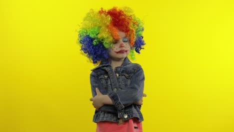 little child girl clown in colorful wig making silly faces. fool around, smiling, dancing. halloween