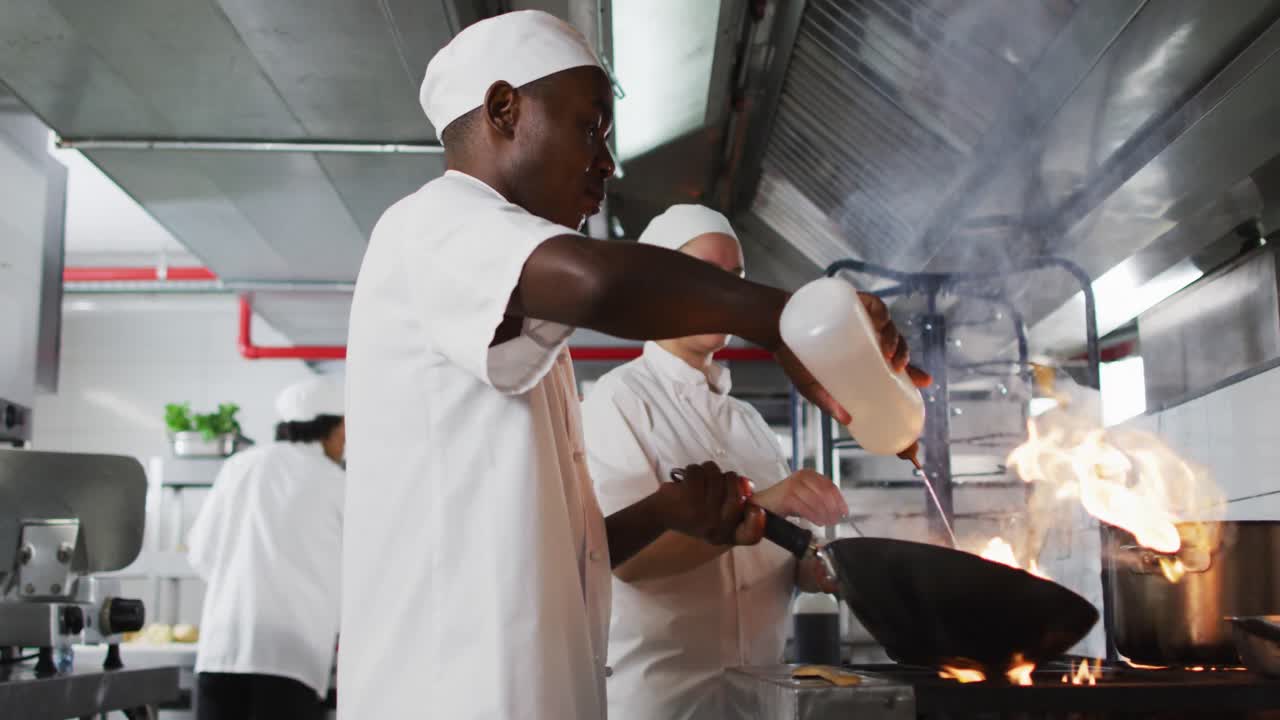 grupo diverso de chefs fritando en sartén en la cocina del restaurante