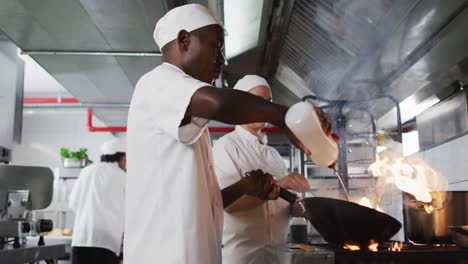 diverse group of chefs frying in pan in restaurant kitchen