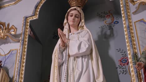 close up of a virgin mary statue with hands in prayer and rosary beads
