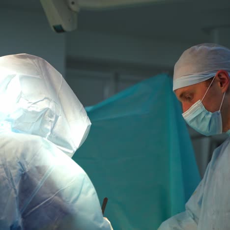 surgery. doctor in medical mask and cap during the operation in the hospital. experienced doctors in protective clothing in the operating theater.