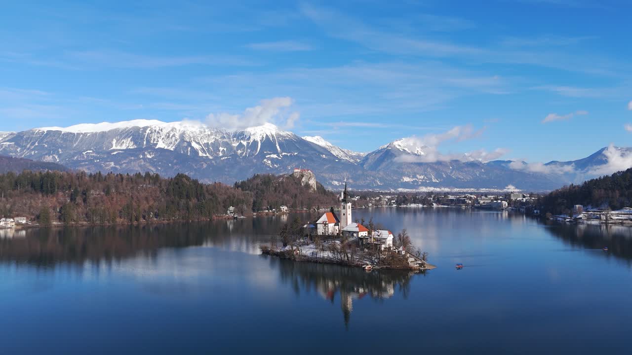 Chiesa dell'isola del lago di Bled e castello in inverno, ripresa aerea con drone del tranquillo lago alpino con montagne innevate e cielo azzurro in Slovenia