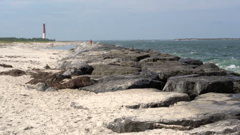 waves breaking on the rocks along the beach with a lighthouse in the background