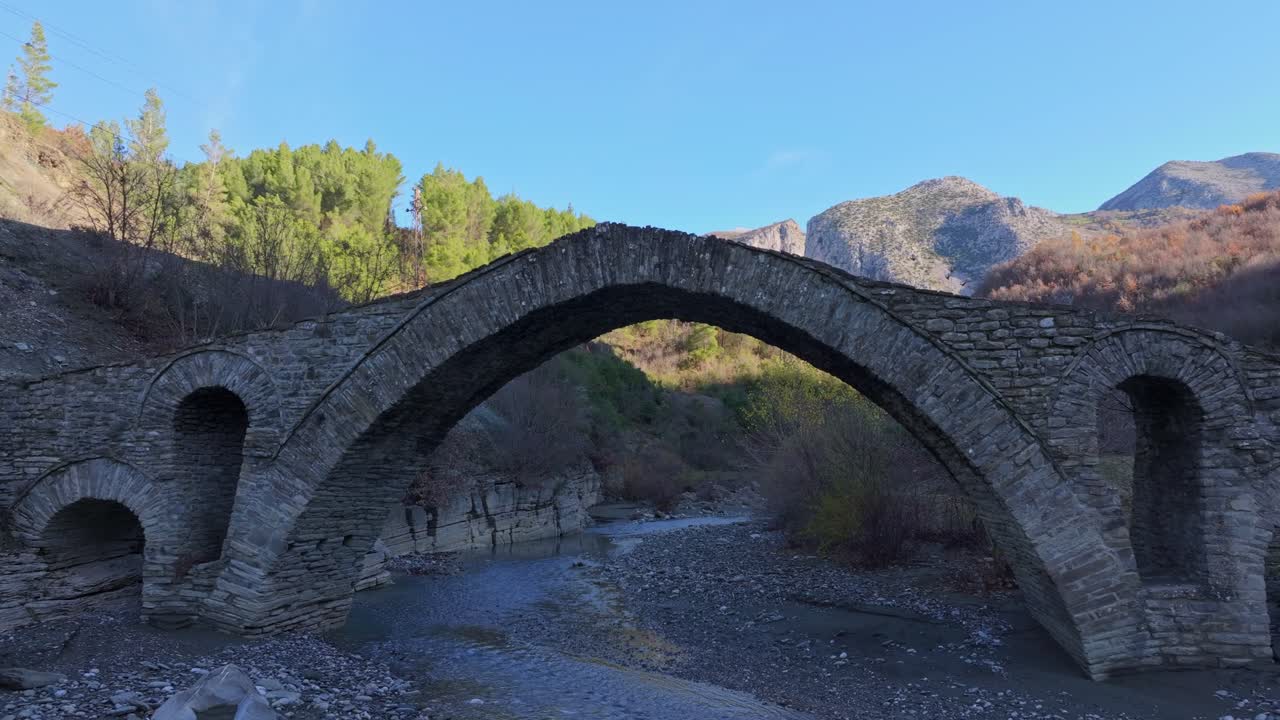 Ripresa aerea di un ponte storico in pietra immerso nella natura rigogliosa, Corovode