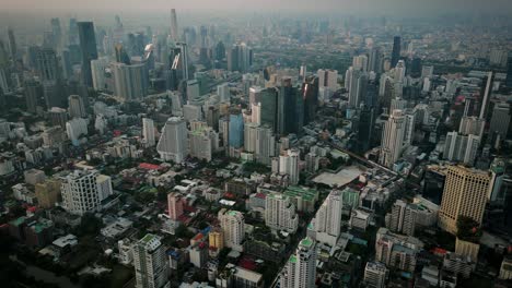 aerial scenic drone footage of the skyline of downtown bangkok, thailand covered in smog during sunset during the smokey burning season