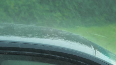 View-of-heavy-storm-hail-and-rain-falling-on-a-black-car,-nature-disaster,-climate-changes,-global-warming,-hot-summer-day,-medium-closeup-shot