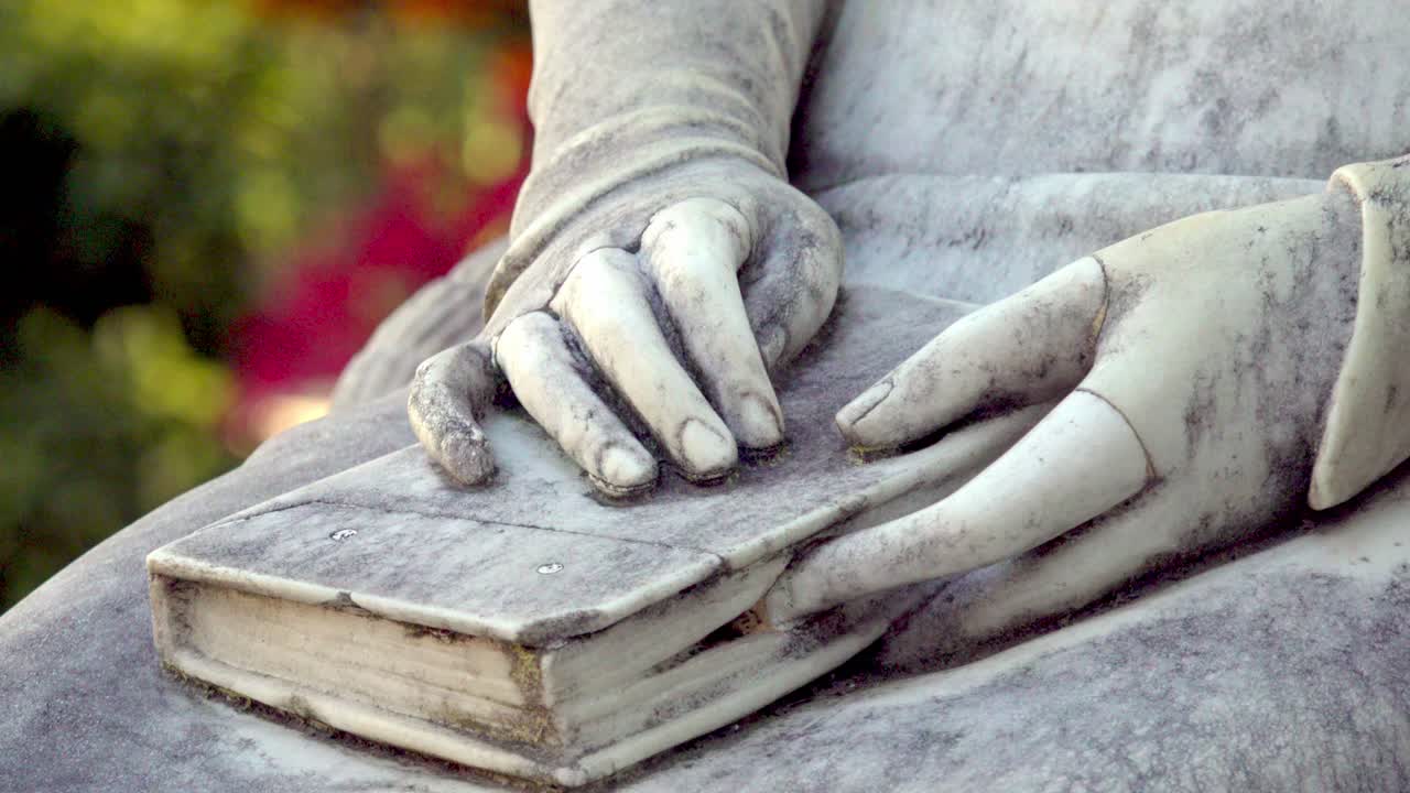 Primo piano di un libro e mani poggiate in grembo