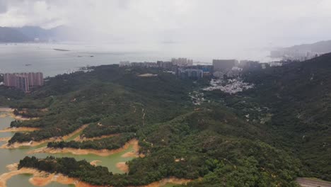 vista aérea paisaje boscoso al lado del embalse de tai lam chung con edificio del paisaje urbano en el fondo en hong kong