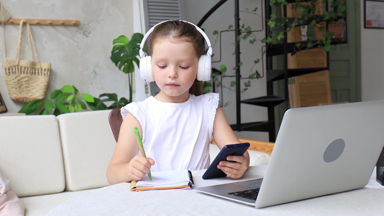 Young Girl with Headphones Studying Online at Home
