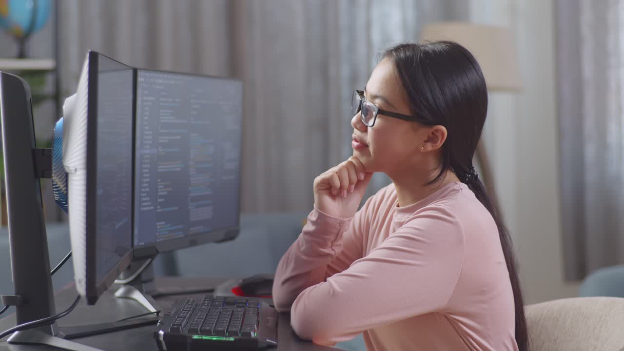 Asian Teen Girl Programmer Thinking About Something And Raising Her Index Finger While Creating Software Engineer Developing App, Program, Video Game On Desktop Computer At Home