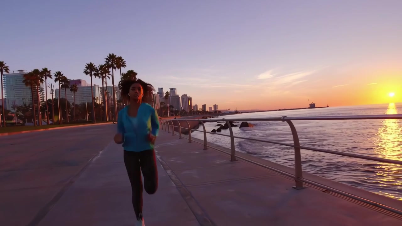 Giovane donna che fa jogging sul lungomare all'alba