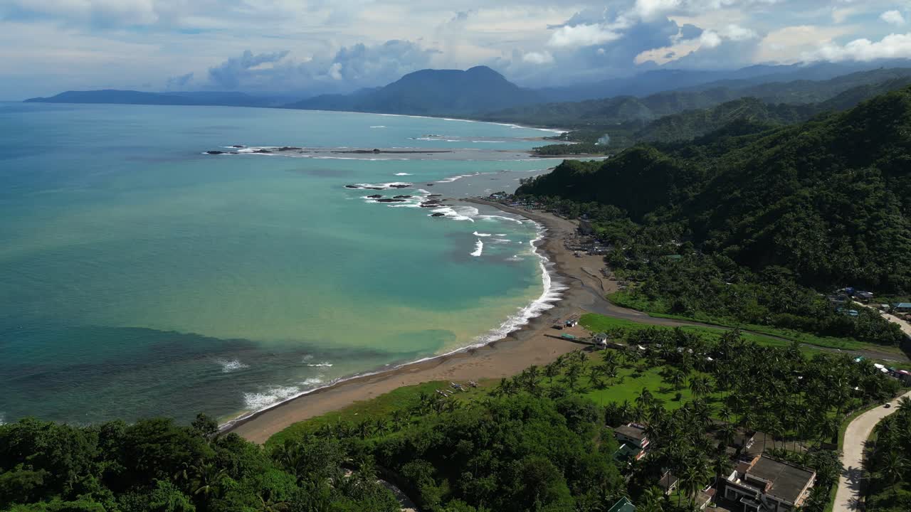 Moving‑out aerial of Dingalan, Aurora, gradually revealing a wider view of compacted green trees covering the hillsides, with the coastline and turquoise sea framing the lush landscape