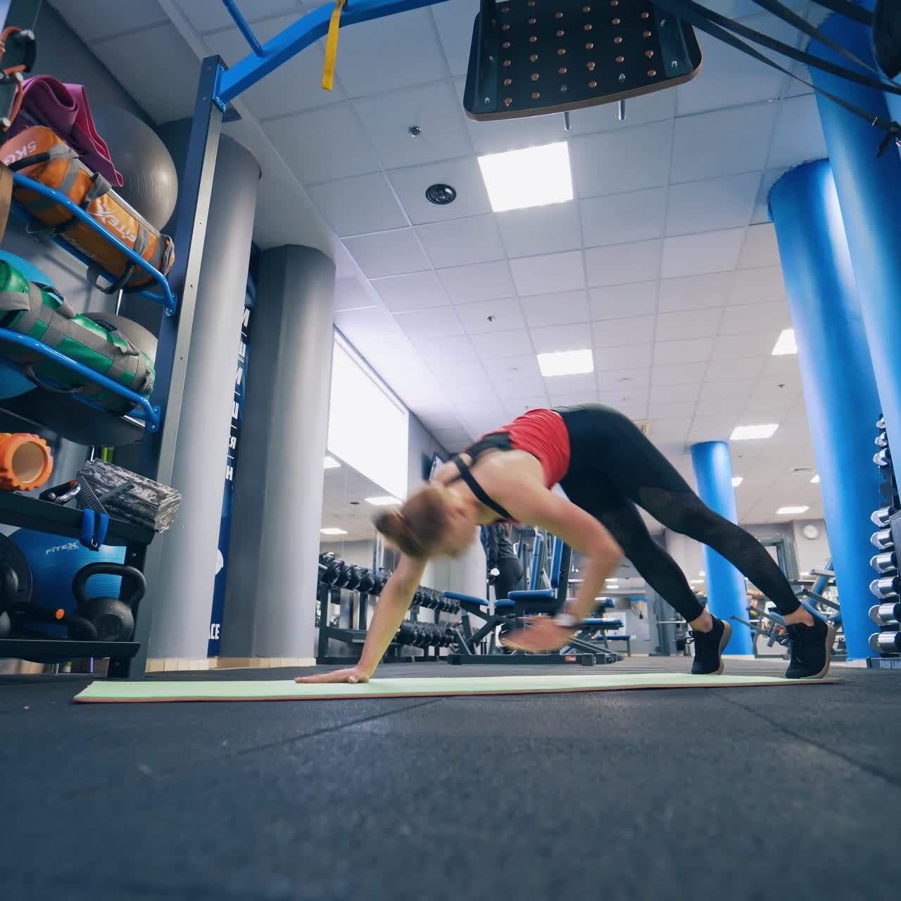 Sports workout in the gym. Young woman in sports suit is doing exercises on the mat in the modern fitness club.