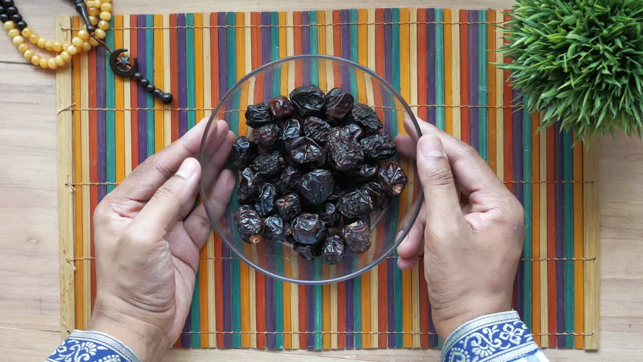 Hands holding a bowl of dates