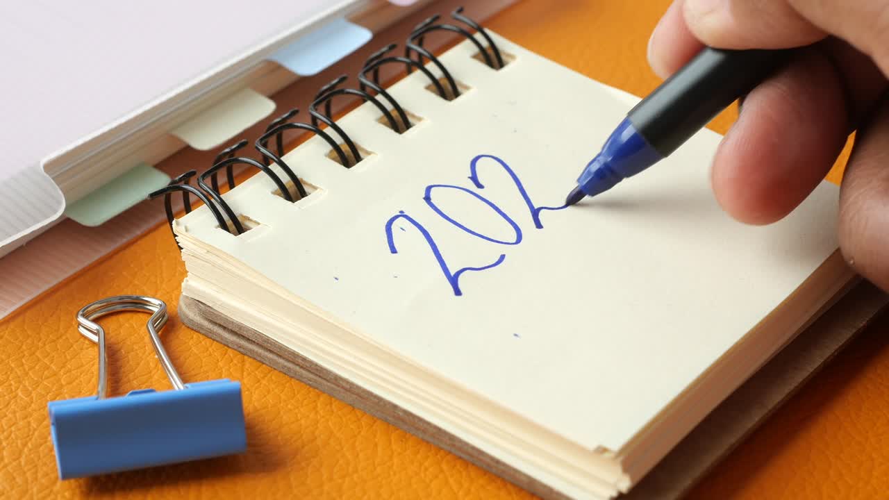 2024 escribiendo a mano en un bloc de notas