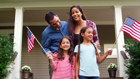 portrait of family outside house holding american flags