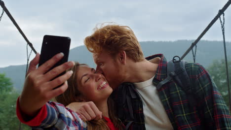 los amantes de la diversión toman fotos en el blog de viajes selfie de teléfonos inteligentes. beso de pareja en las montañas