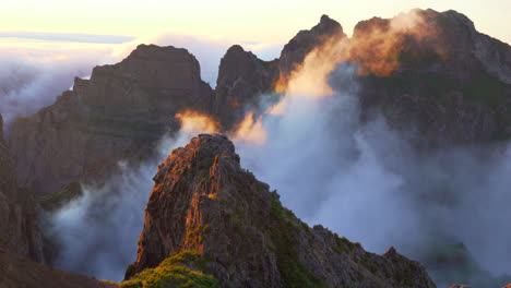 fog slowly moving over mountain peaks. magic hour