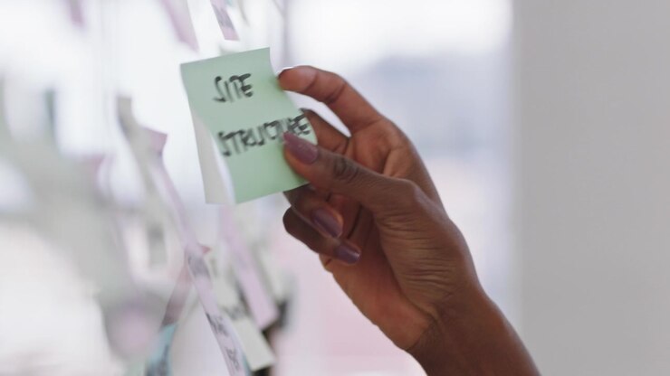 Donna professionista che organizza post-it sulla parete di vetro dell'ufficio