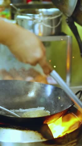 chef skillfully cooks with a wok in kitchen